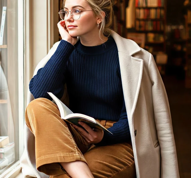 A writer reviewing a manuscript by a window